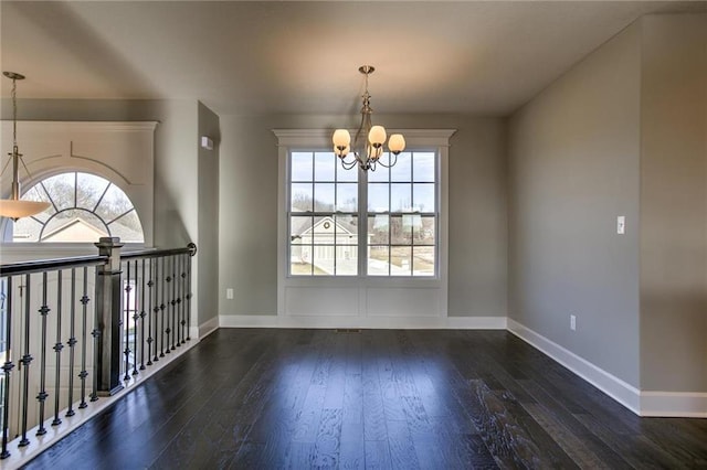 empty room featuring baseboards, an inviting chandelier, and hardwood / wood-style floors