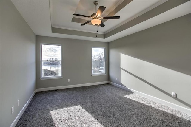 carpeted empty room featuring a raised ceiling, crown molding, a healthy amount of sunlight, and baseboards