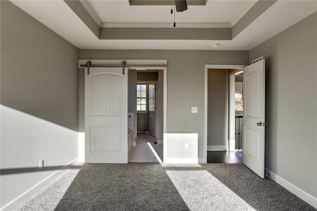 unfurnished bedroom featuring carpet flooring, a raised ceiling, a barn door, and ornamental molding