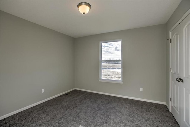 unfurnished bedroom featuring baseboards and dark colored carpet