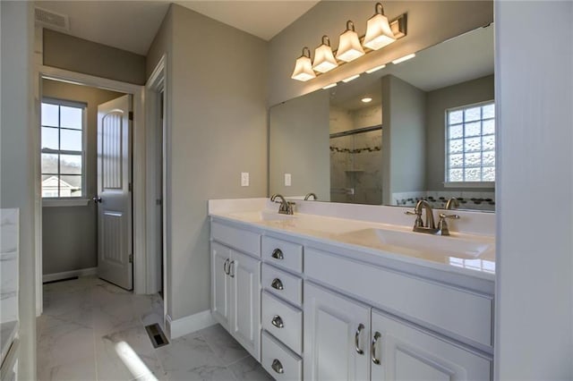 full bath featuring a sink, marble finish floor, a stall shower, and double vanity