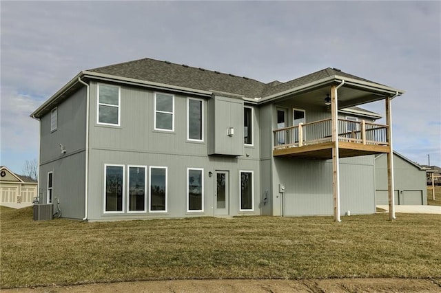 rear view of house with central AC unit, a yard, a ceiling fan, and a shingled roof