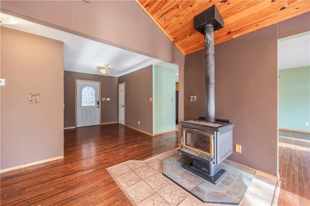 living room with hardwood / wood-style flooring, a wood stove, wooden ceiling, and vaulted ceiling