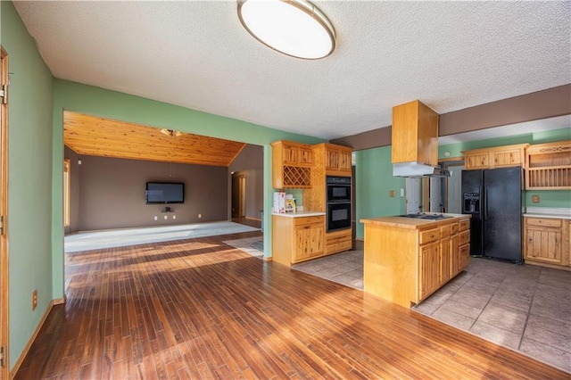 kitchen featuring a textured ceiling, black appliances, lofted ceiling, wooden counters, and light hardwood / wood-style floors