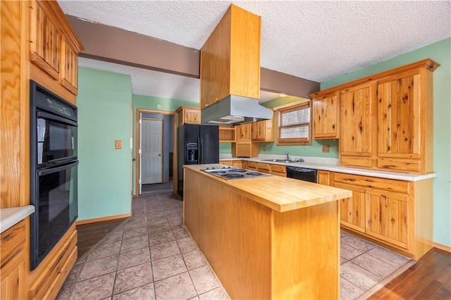 kitchen with wooden counters, a textured ceiling, a kitchen island, black appliances, and sink