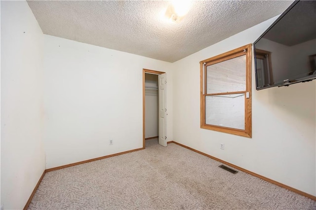 unfurnished bedroom featuring light carpet, a closet, and a textured ceiling