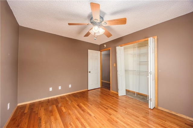 unfurnished bedroom with ceiling fan, a closet, a textured ceiling, and light hardwood / wood-style flooring