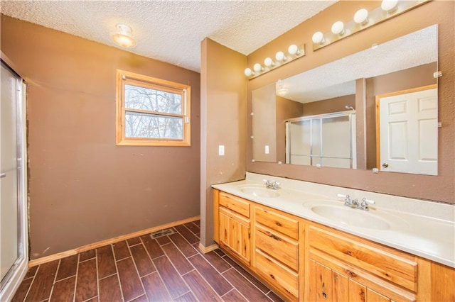 bathroom featuring a textured ceiling, an enclosed shower, and vanity