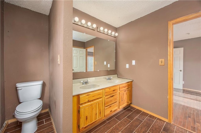 bathroom featuring a textured ceiling, toilet, and vanity