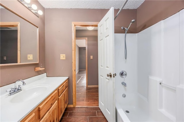 bathroom with a textured ceiling, vanity, and  shower combination