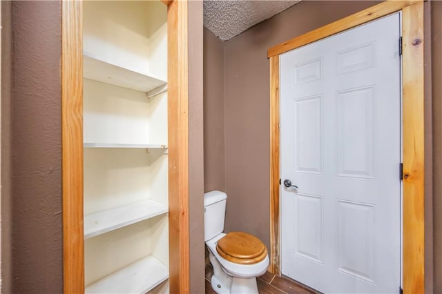 bathroom with toilet, a textured ceiling, and hardwood / wood-style floors