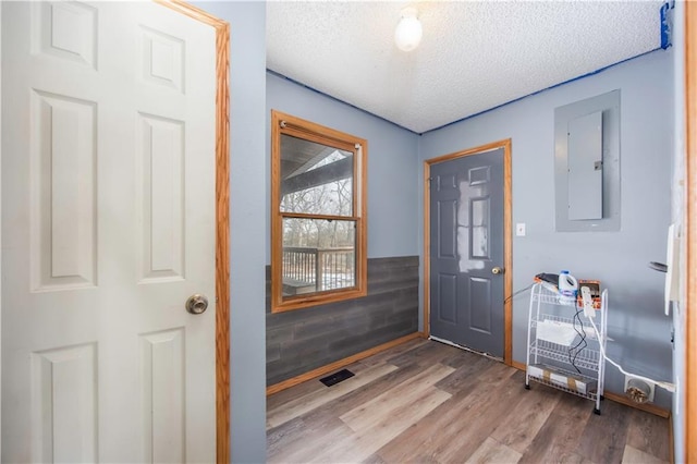 entryway with light hardwood / wood-style floors, a textured ceiling, and electric panel