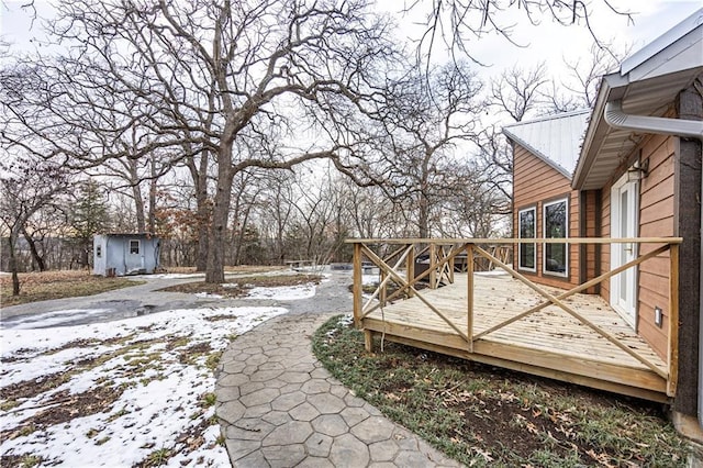 yard layered in snow featuring a deck and an outbuilding