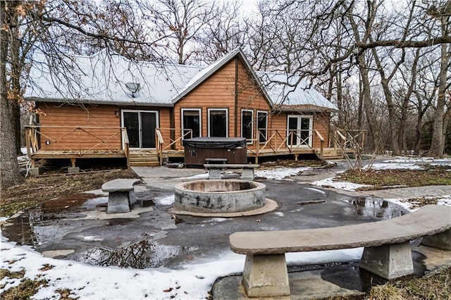 snow covered house with a hot tub and a deck