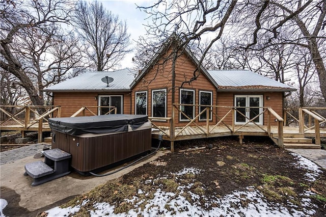 snow covered house featuring a deck and a hot tub