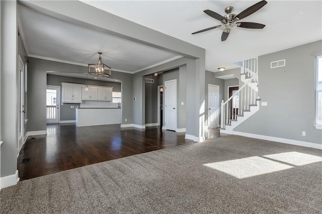 unfurnished living room with ornamental molding, dark hardwood / wood-style flooring, and ceiling fan with notable chandelier