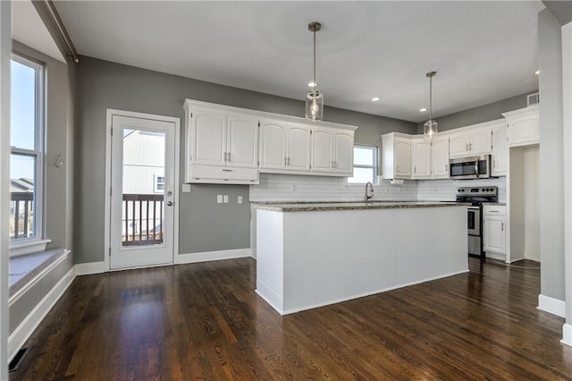 kitchen with appliances with stainless steel finishes, dark hardwood / wood-style floors, decorative light fixtures, white cabinetry, and backsplash