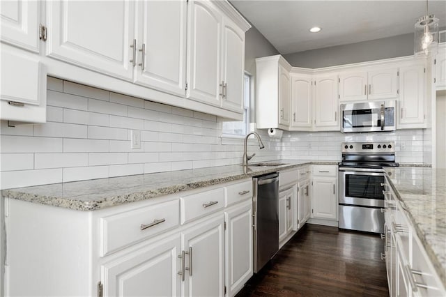 kitchen featuring sink, appliances with stainless steel finishes, white cabinetry, dark hardwood / wood-style floors, and light stone countertops