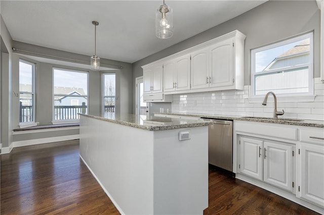 kitchen featuring sink, white cabinetry, decorative light fixtures, stainless steel dishwasher, and a kitchen island