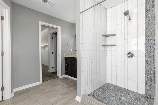 bathroom featuring vanity, hardwood / wood-style floors, and tiled shower