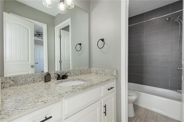 full bathroom with vanity, tiled shower / bath, and toilet