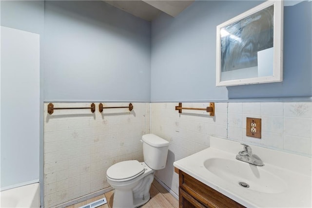 bathroom with toilet, tile walls, and vanity