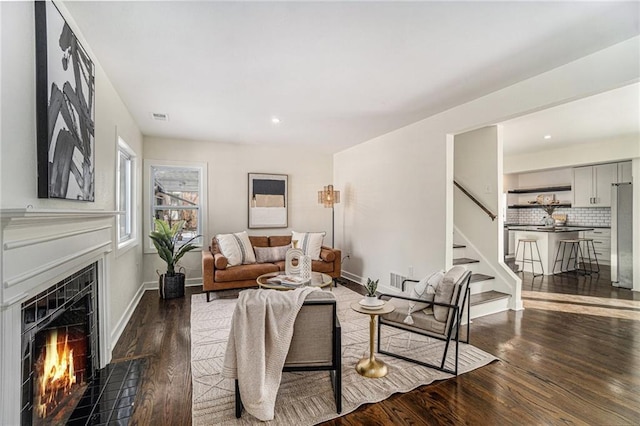 living room with dark hardwood / wood-style floors and a tiled fireplace