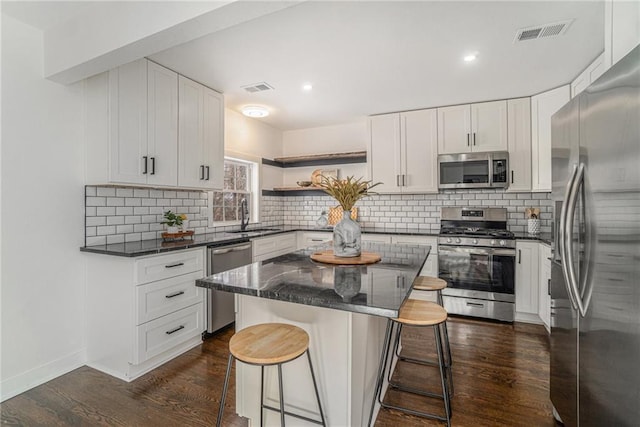 kitchen featuring white cabinets, a center island, appliances with stainless steel finishes, dark hardwood / wood-style flooring, and sink