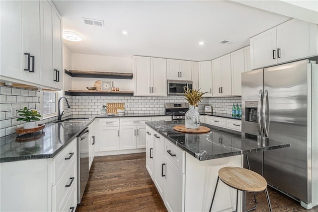 kitchen with white cabinets, a kitchen island, sink, stainless steel appliances, and dark hardwood / wood-style floors