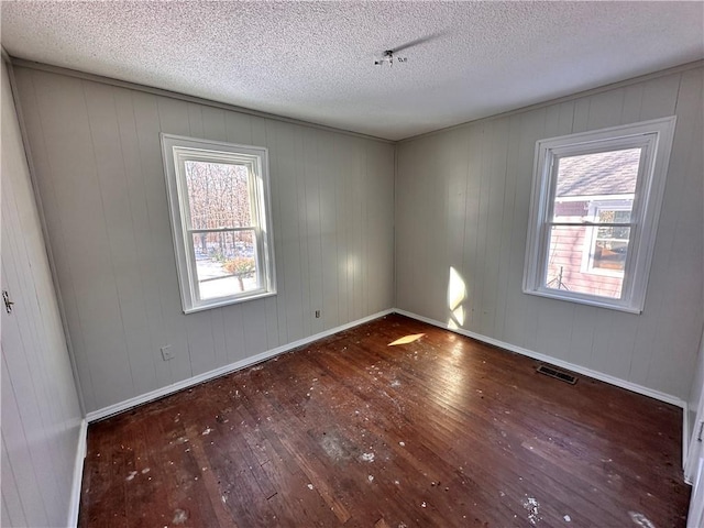 spare room featuring dark hardwood / wood-style flooring and a textured ceiling