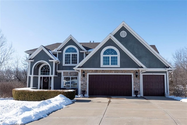 view of front of property featuring driveway, stone siding, and stucco siding