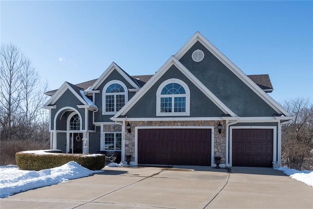 view of front of house with concrete driveway, stone siding, and stucco siding