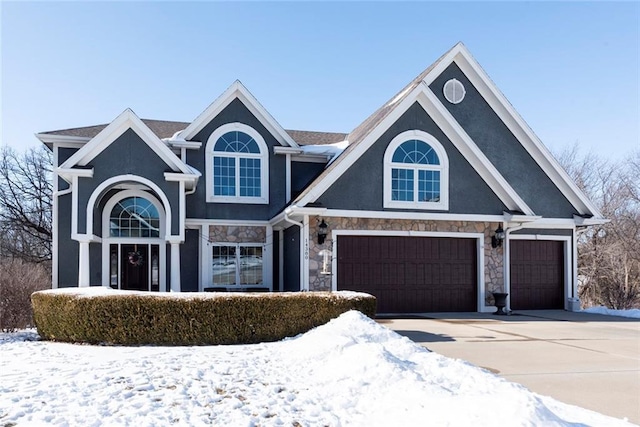 traditional home with a garage, stone siding, concrete driveway, and stucco siding