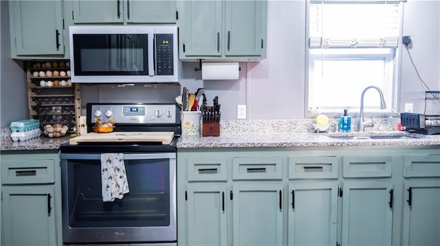 kitchen with sink, stainless steel appliances, and light stone countertops