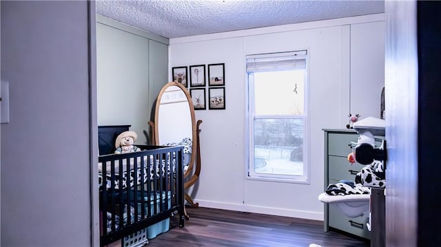 bedroom featuring a crib, a textured ceiling, and dark hardwood / wood-style floors