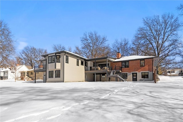 snow covered rear of property with a balcony