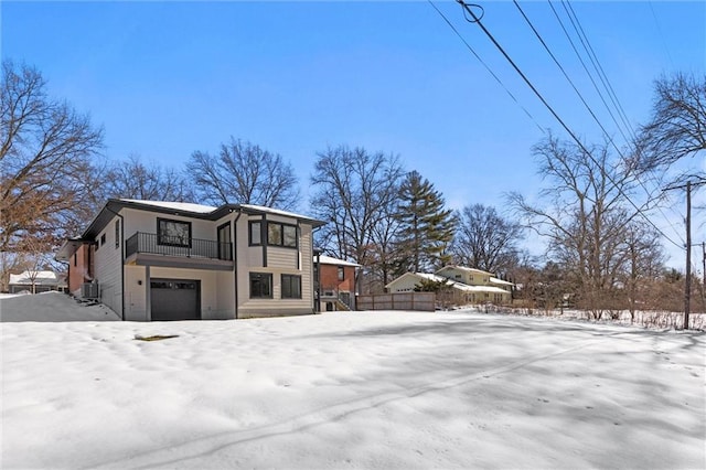 view of snow covered exterior with a balcony, a garage, and central air condition unit