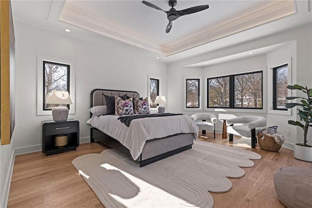 bedroom with a tray ceiling, light hardwood / wood-style flooring, and ceiling fan