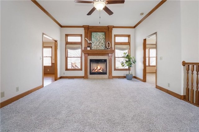 unfurnished living room featuring crown molding, light colored carpet, ceiling fan, and a fireplace