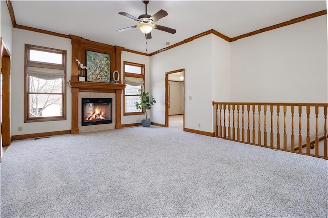 unfurnished living room featuring ornamental molding, a large fireplace, light colored carpet, and ceiling fan