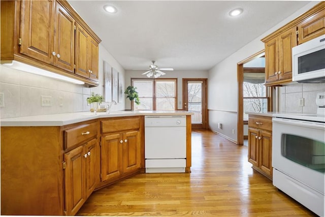 kitchen featuring sink, decorative backsplash, ceiling fan, light hardwood / wood-style floors, and white appliances