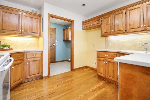 kitchen with tasteful backsplash, sink, white electric range, and light wood-type flooring