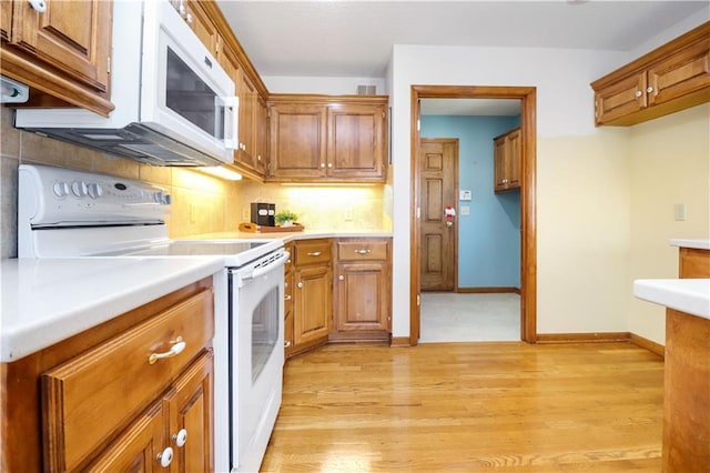 kitchen with tasteful backsplash, white appliances, and light hardwood / wood-style floors