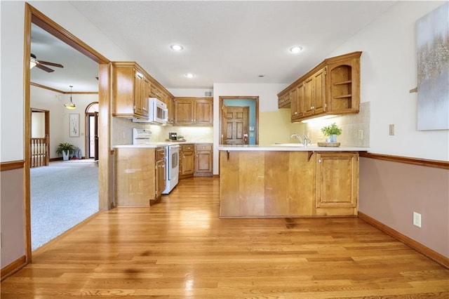 kitchen featuring backsplash, white appliances, kitchen peninsula, and light wood-type flooring