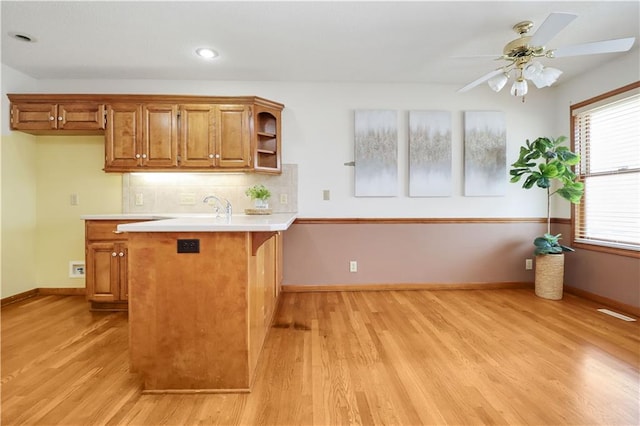 kitchen with sink, light hardwood / wood-style flooring, ceiling fan, tasteful backsplash, and kitchen peninsula