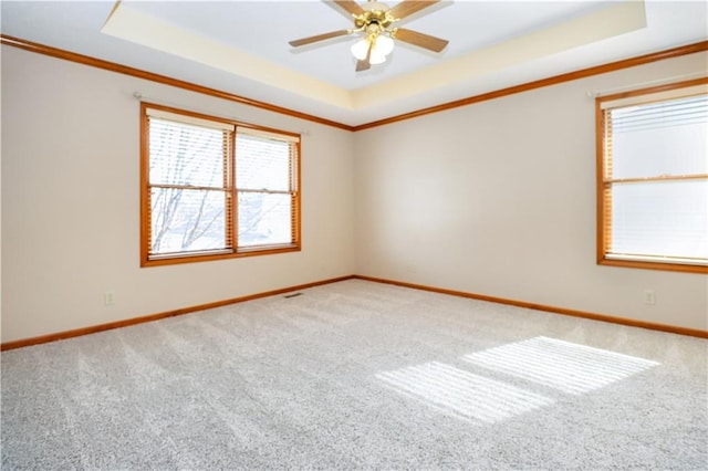 carpeted empty room with ornamental molding, ceiling fan, and a tray ceiling