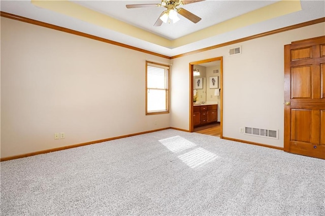 carpeted empty room featuring ornamental molding, ceiling fan, and a tray ceiling