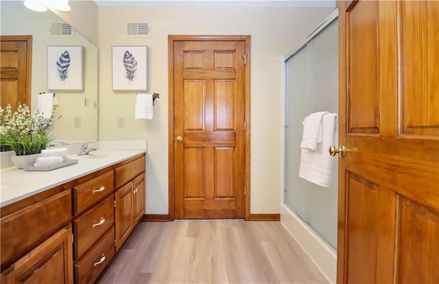 bathroom featuring an enclosed shower, vanity, and wood-type flooring