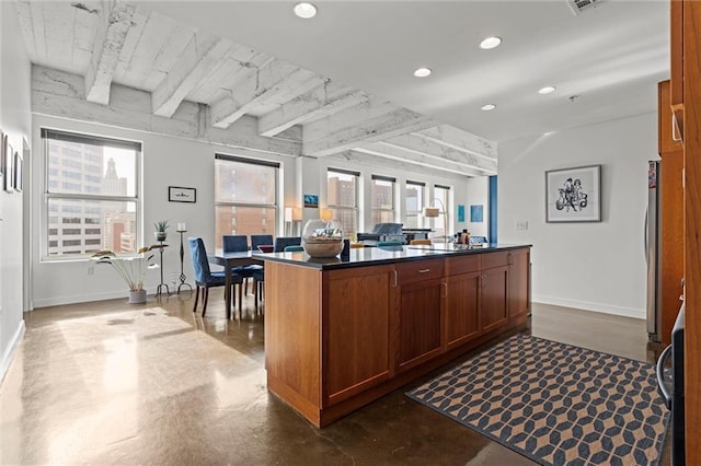 kitchen featuring a center island, finished concrete flooring, dark countertops, recessed lighting, and freestanding refrigerator