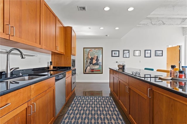 kitchen featuring stainless steel appliances, dark countertops, visible vents, and a sink